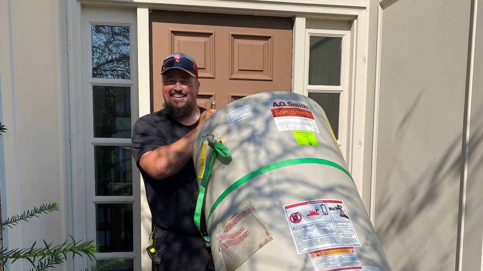 Plumber moving a new water heater on a dolly to a home's front door