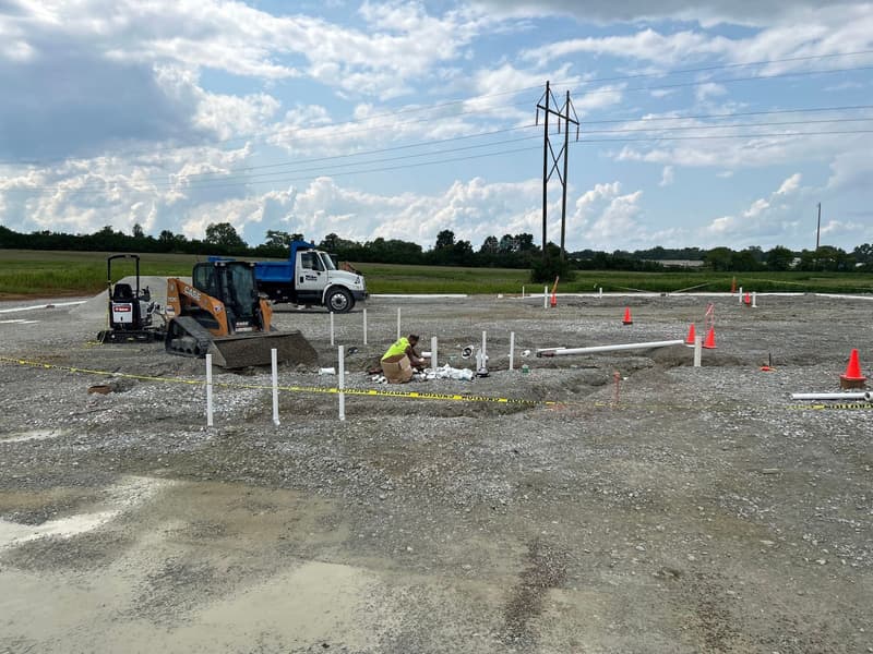 Job site with excavator, truck and plumbing stubs